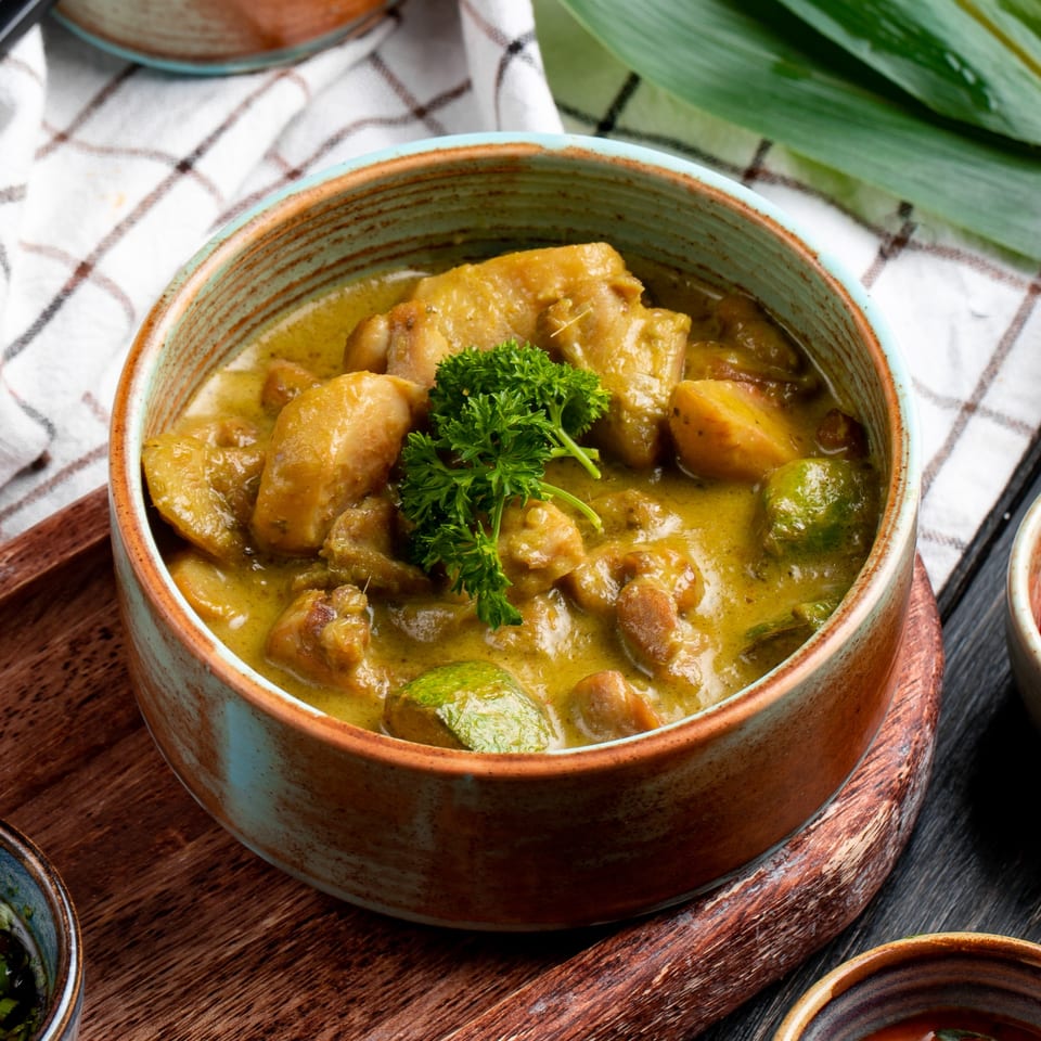 Nepalese chicken curry with potatoes and green vegetables, garnished with parsley, in a rustic bowl.
